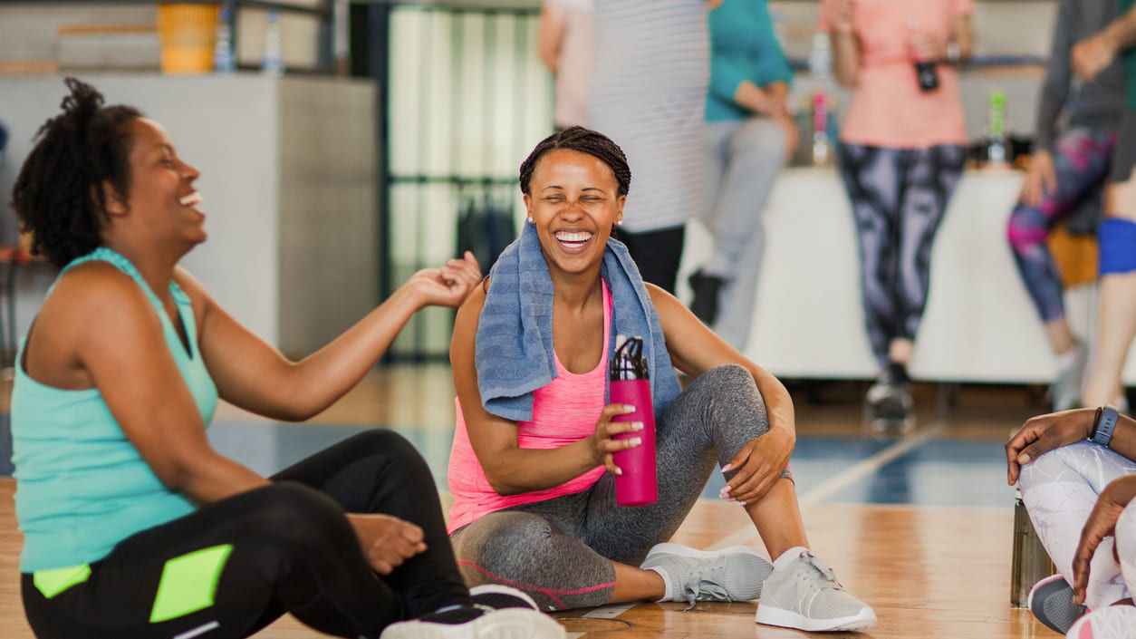 A group of people sitting on the floor in a gym.