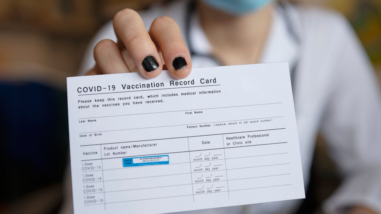 A woman holding up a paper with the word covid in it.