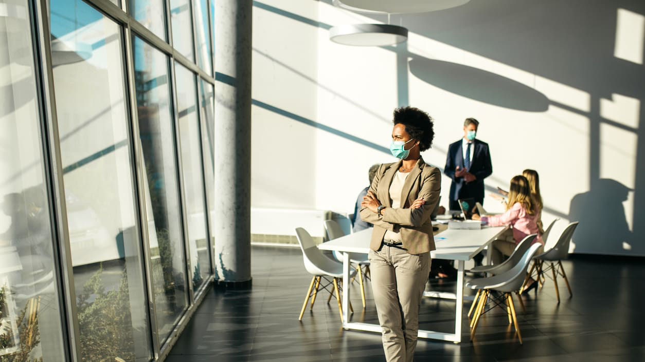 A business woman wearing a face mask in a conference room.