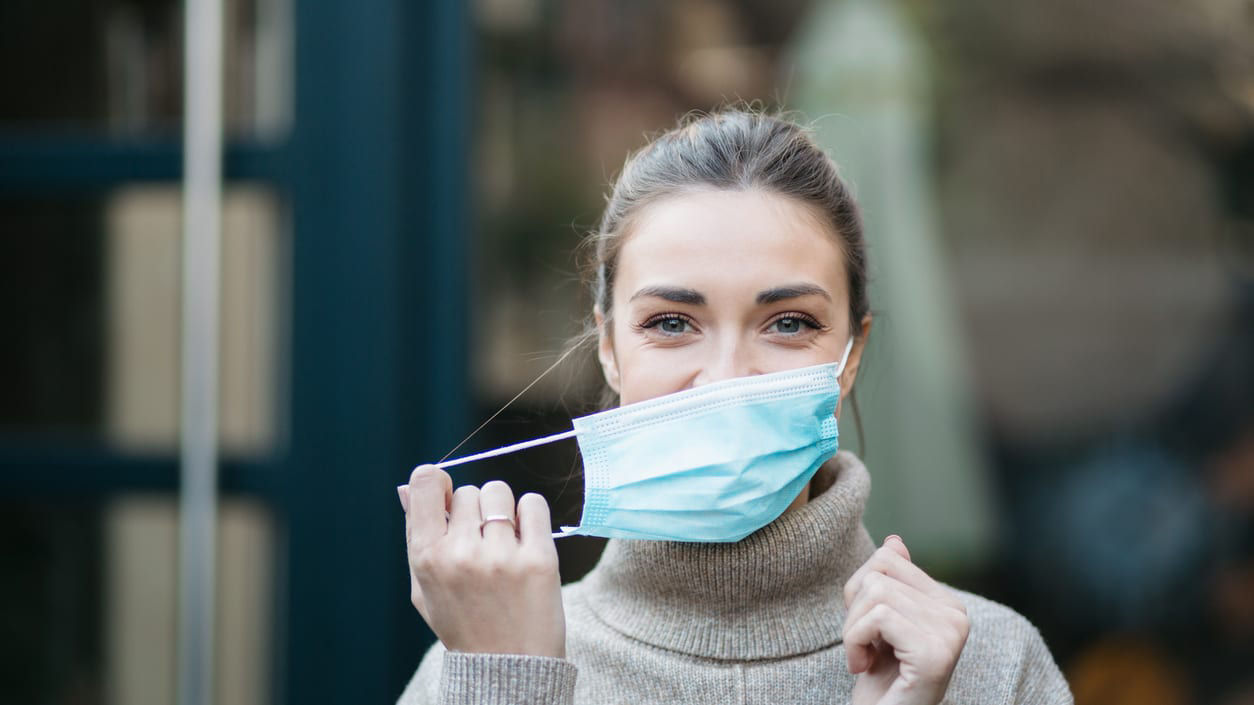A woman wearing a surgical mask outside.