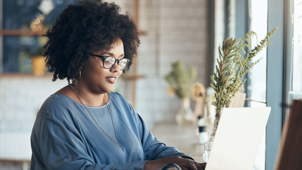 A woman working on a laptop in a coffee shop.