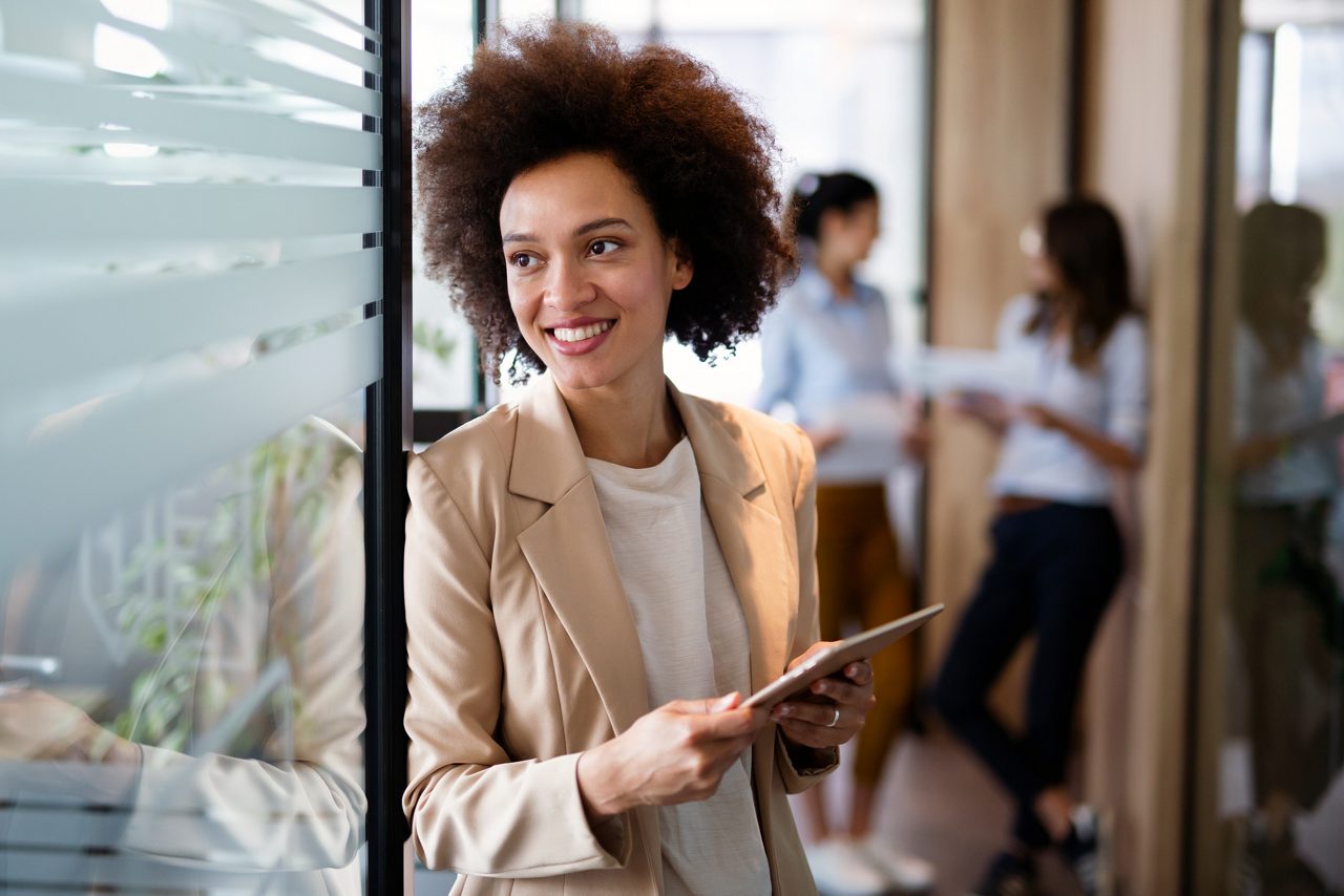 Portrait of young successful african american woman working with tablet in office