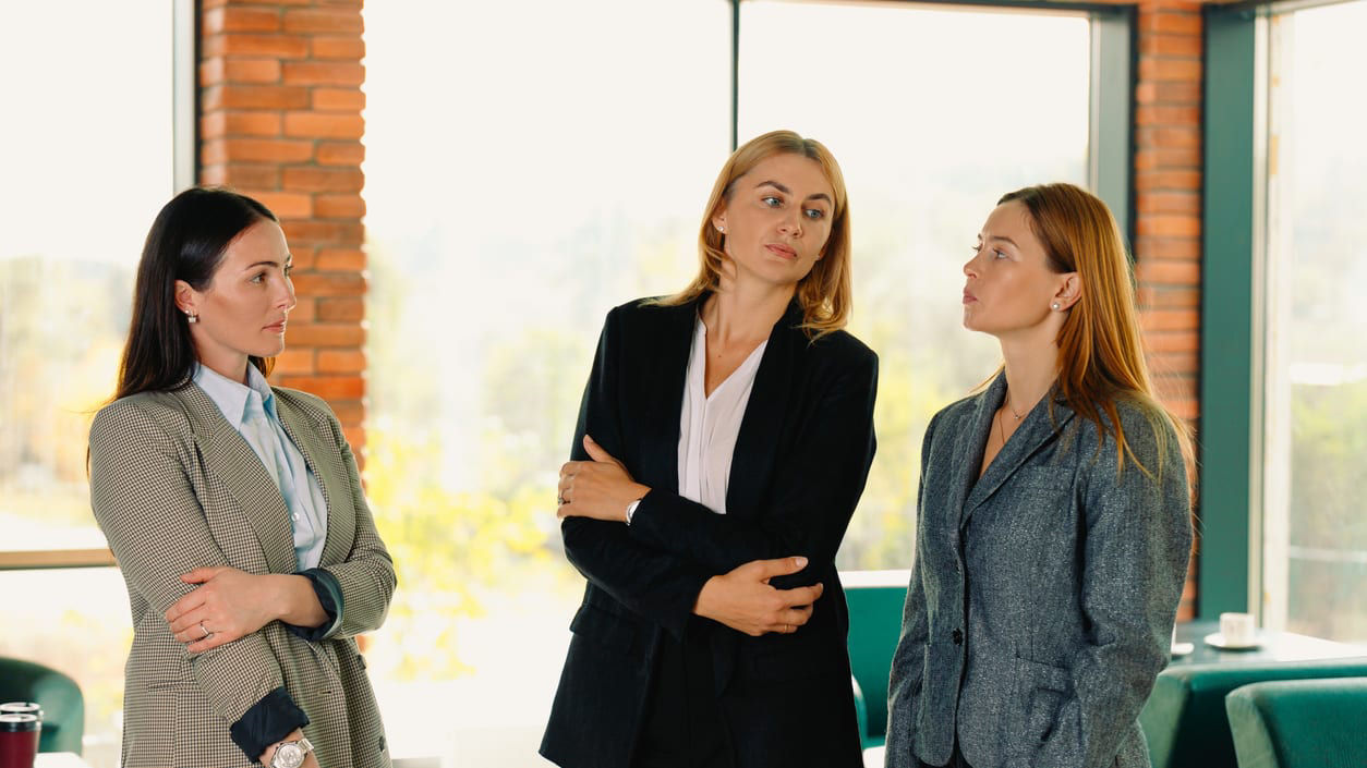 Three business women standing in a conference room.