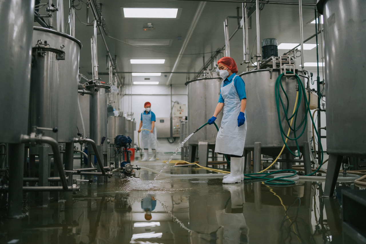 Factory worker cleaning flooring Factory interior storage tank section Filtering Machine and Tanks after production completed