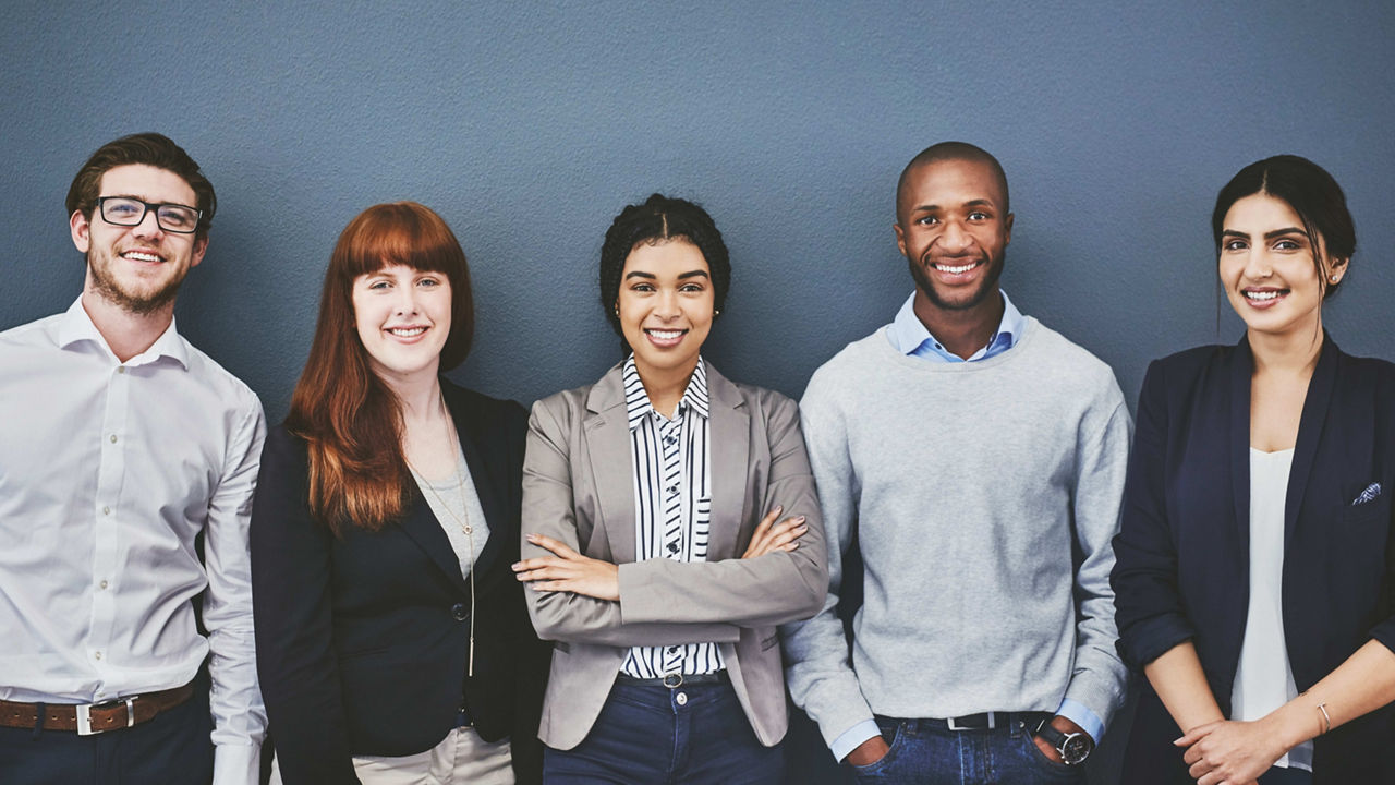 A group of business people standing in front of a gray wall.