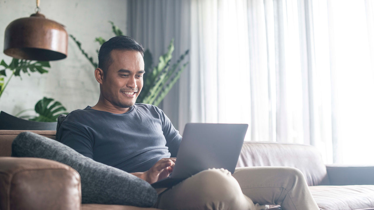 A man sitting on a couch using a laptop.