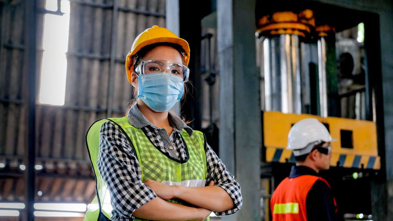 Two women wearing protective masks in a factory.