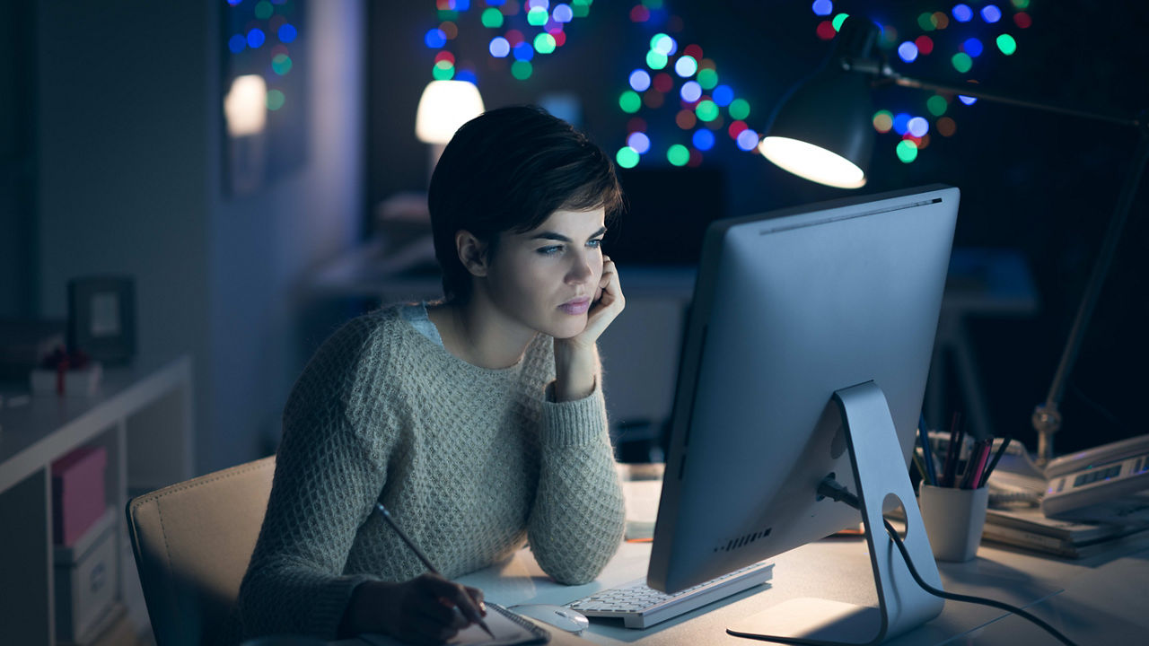 A woman is working on her computer at night.