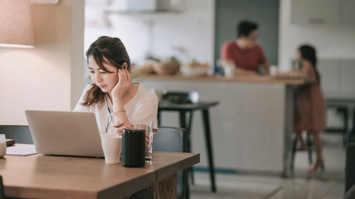 A woman is sitting at a table working on her laptop.