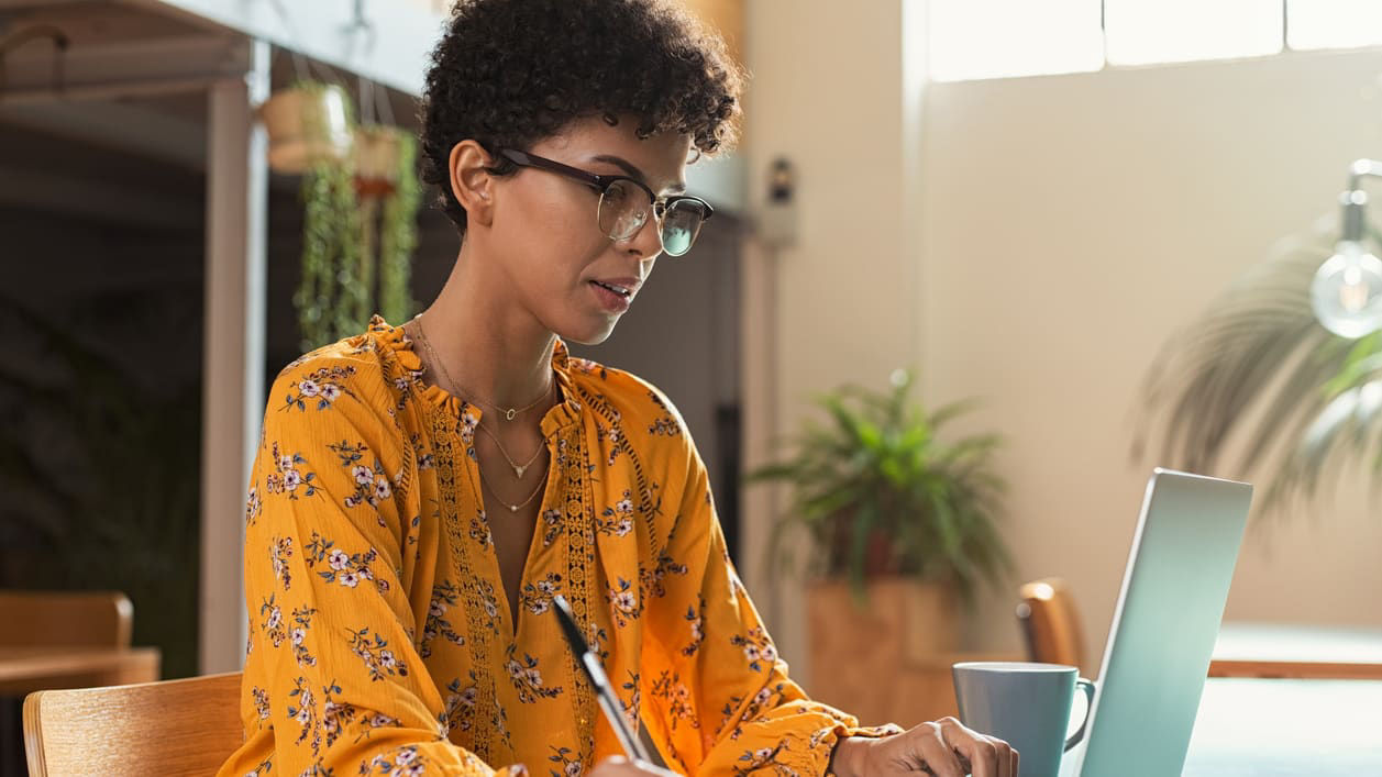 A woman working on her laptop in a coffee shop.