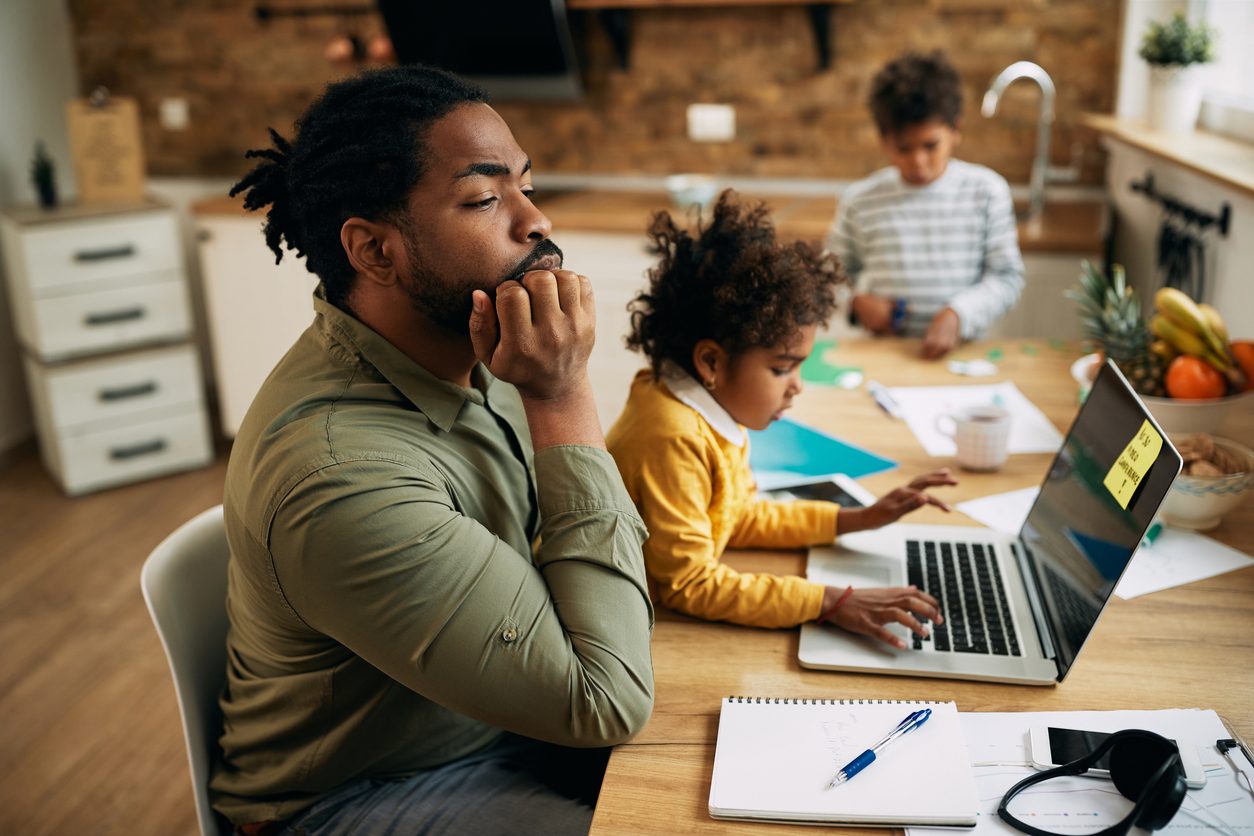 man working at home but is distracted by his two small children