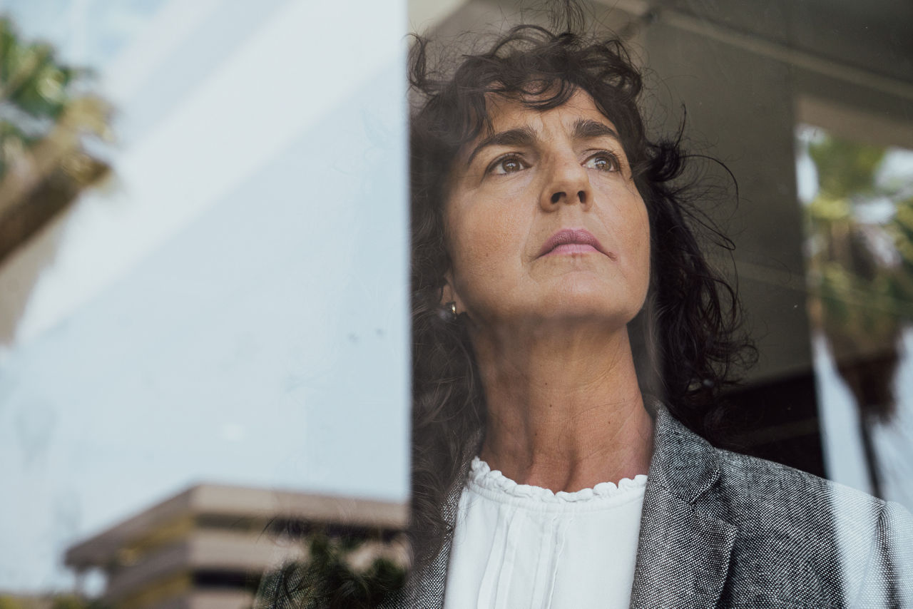 Mature businesswoman contemplating and looking through the window at office