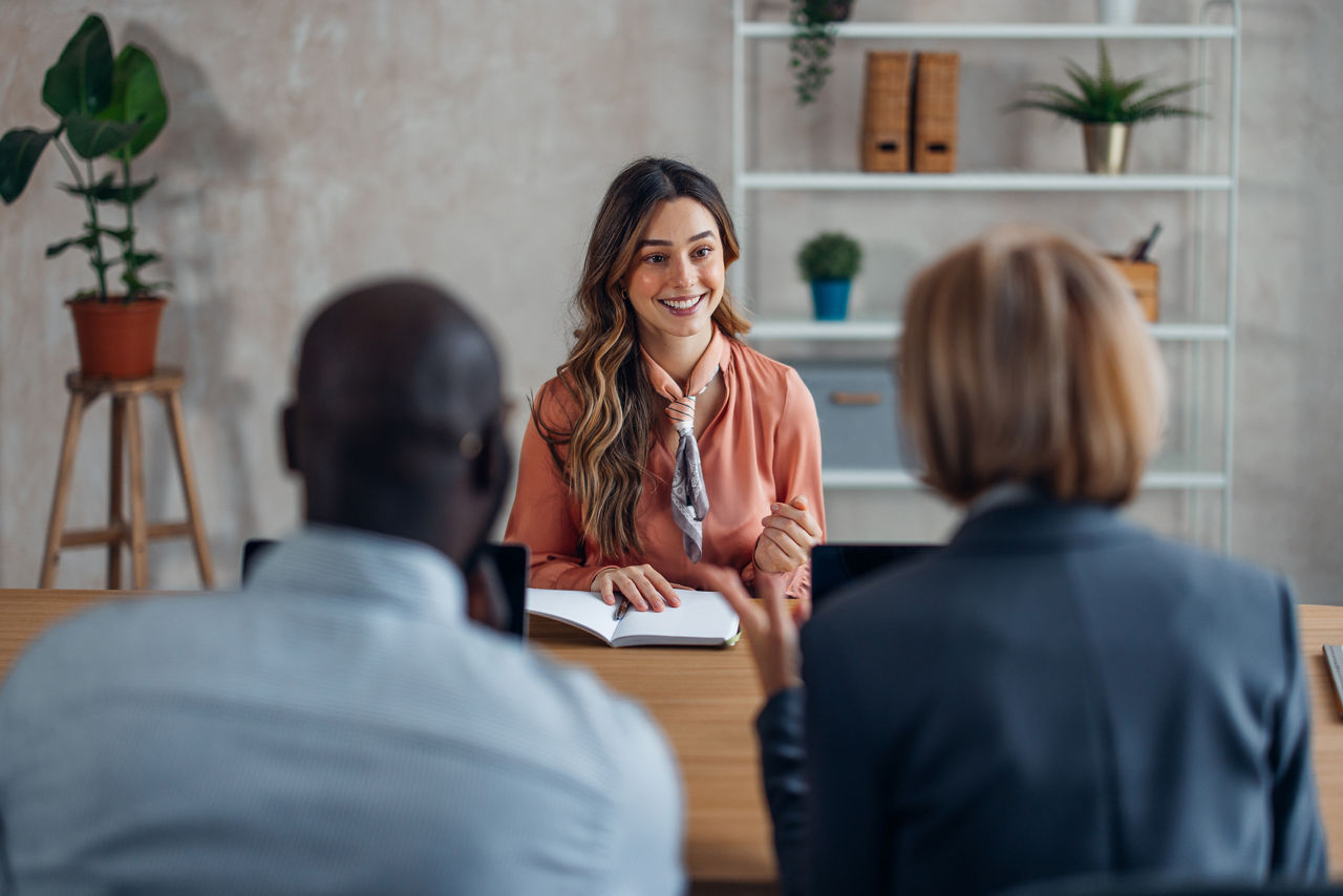 A confident professional woman discussing points with colleagues, showcasing effective communication and engagement in a collaborative workspace atmosphere during a meeting.
