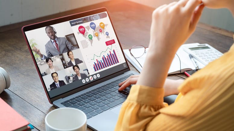 A woman is using a laptop to watch a video conference.