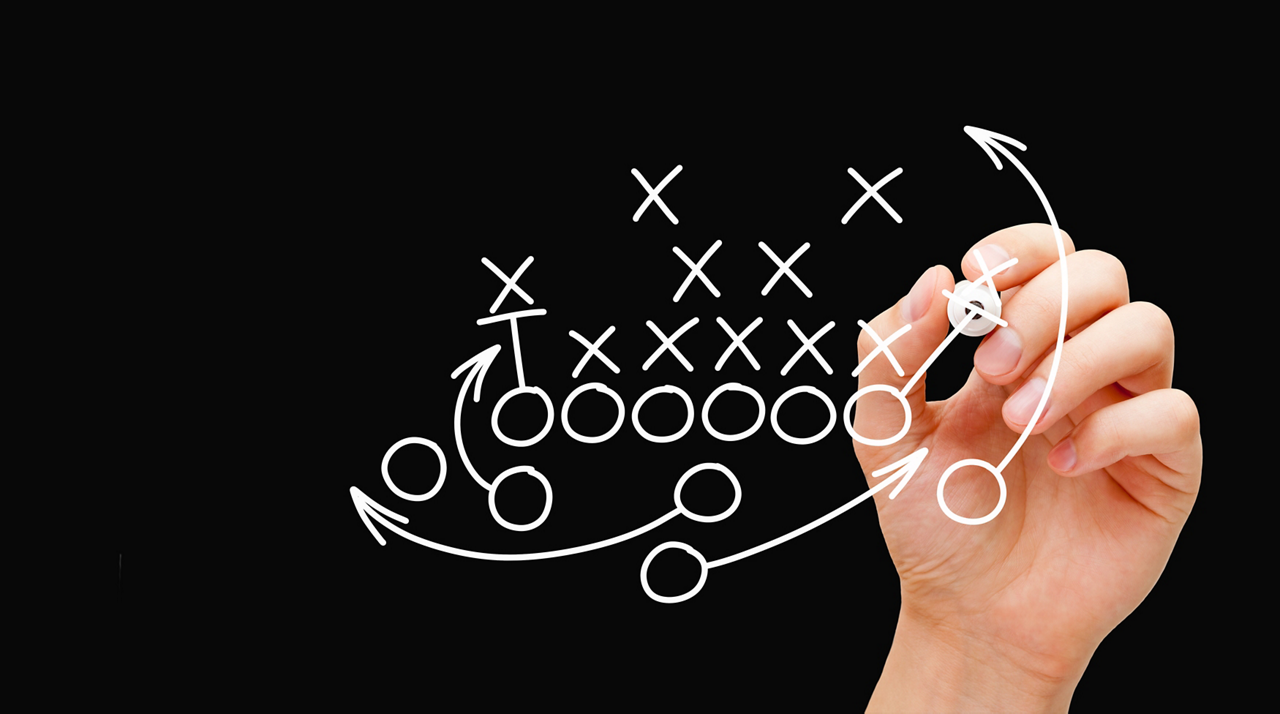 Coach drawing american football or rugby game plan, strategy and tactics with white marker on transparent wipe board.