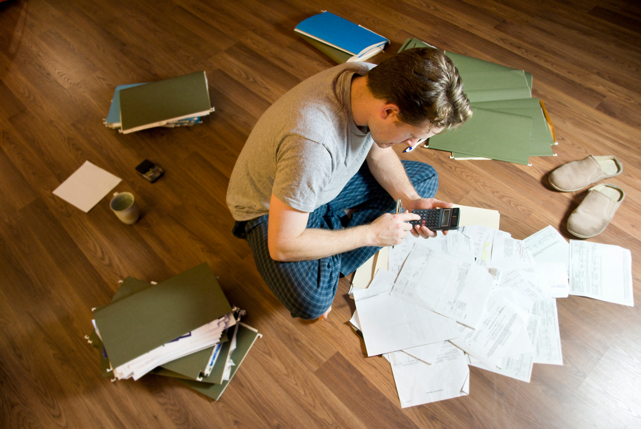 a lot of papers / the man prepares his taxes / sitting in the floor