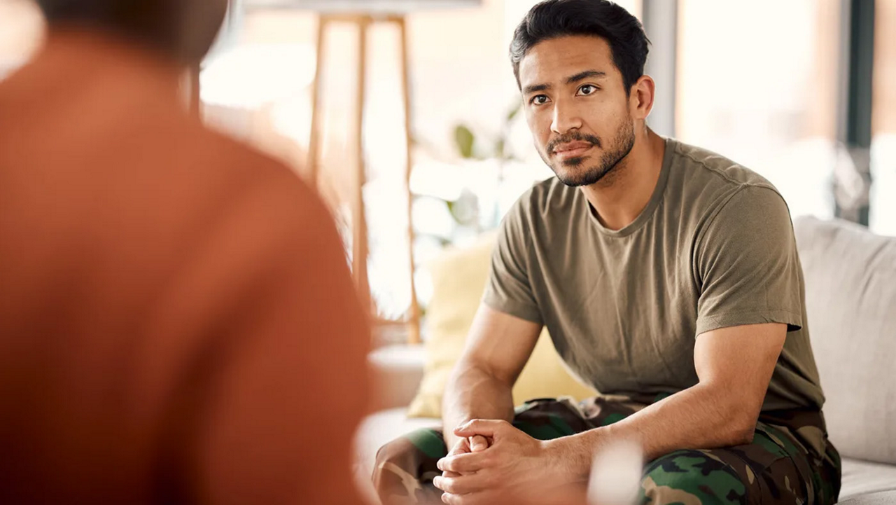 veteran sitting on a couch speaking with someone