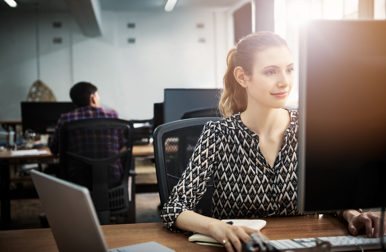 Shot of a young woman using a computer at her desk in a modern office