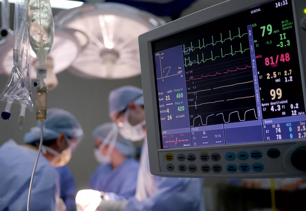 Doctors and nurses treating a patient as their vitals are displayed on a monitor
