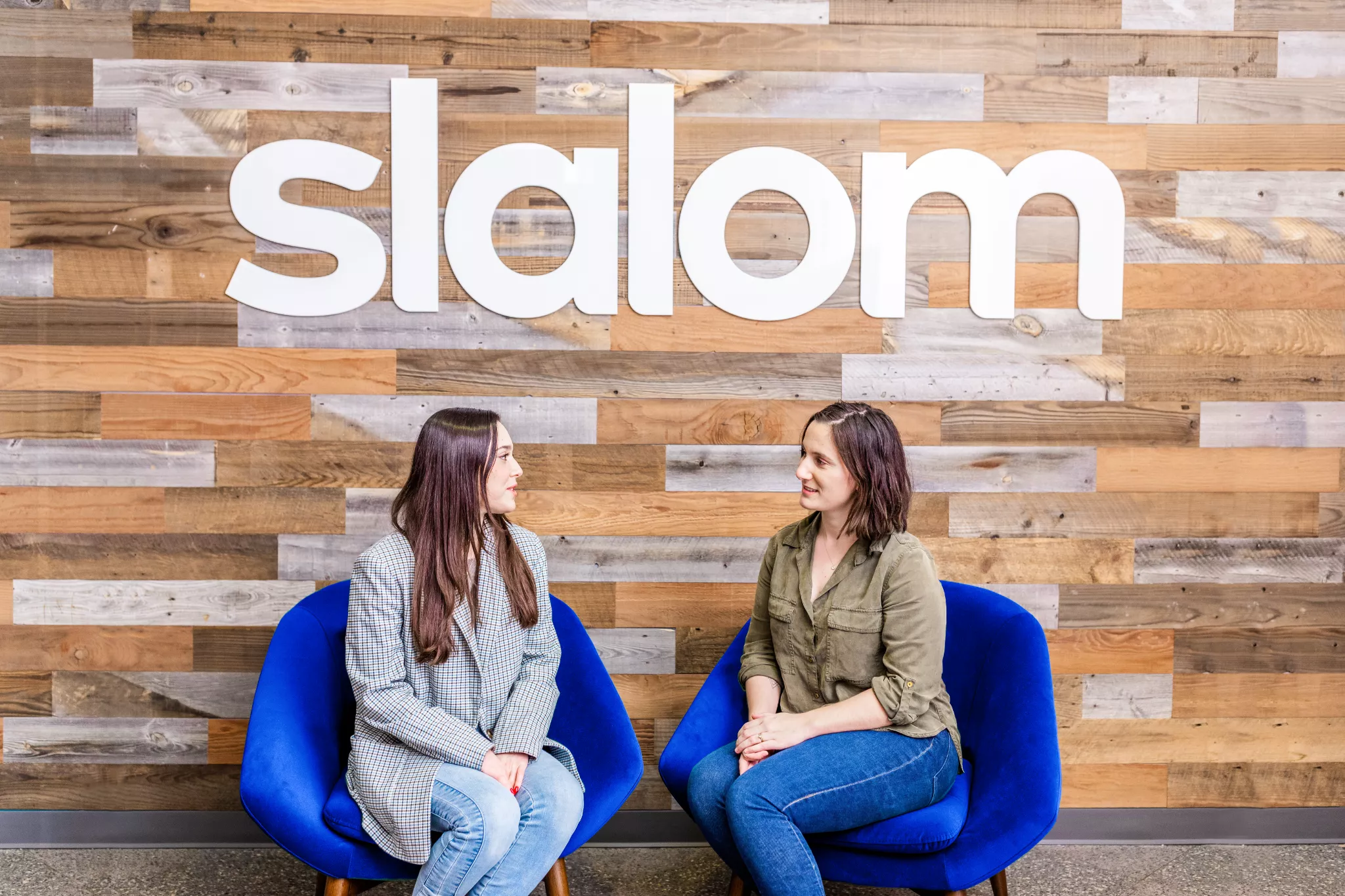 Two women sitting in blue chairs talking