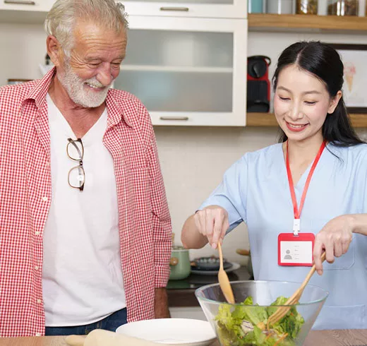 Female caregiver who was screened using GenAI solution helping elderly man prepare dinner in his home