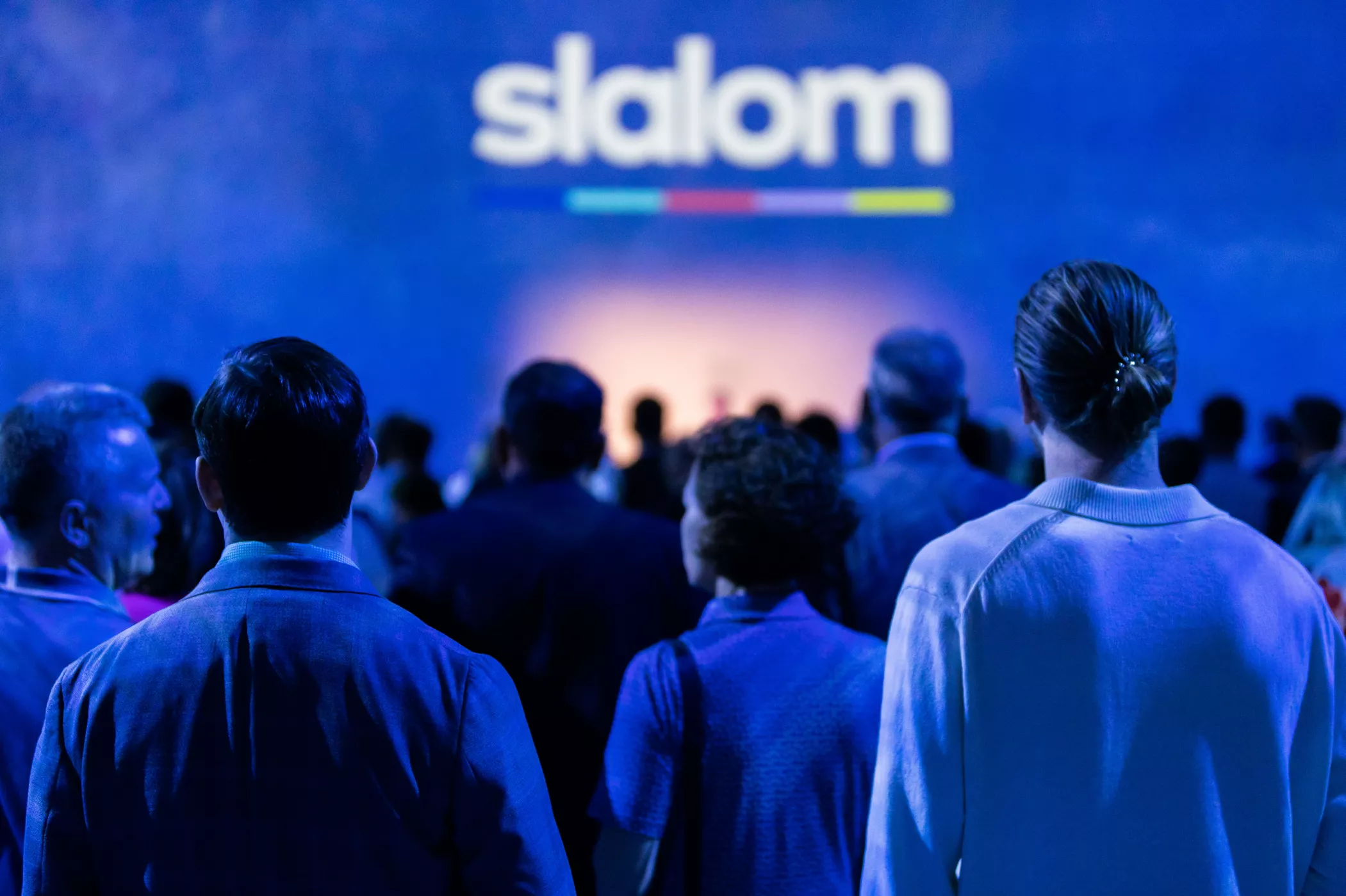 People surrounding a stage with the Slalom logo on the screen.