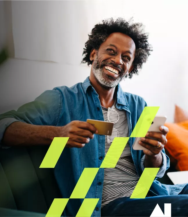 man smiling while holding his credit card and phone