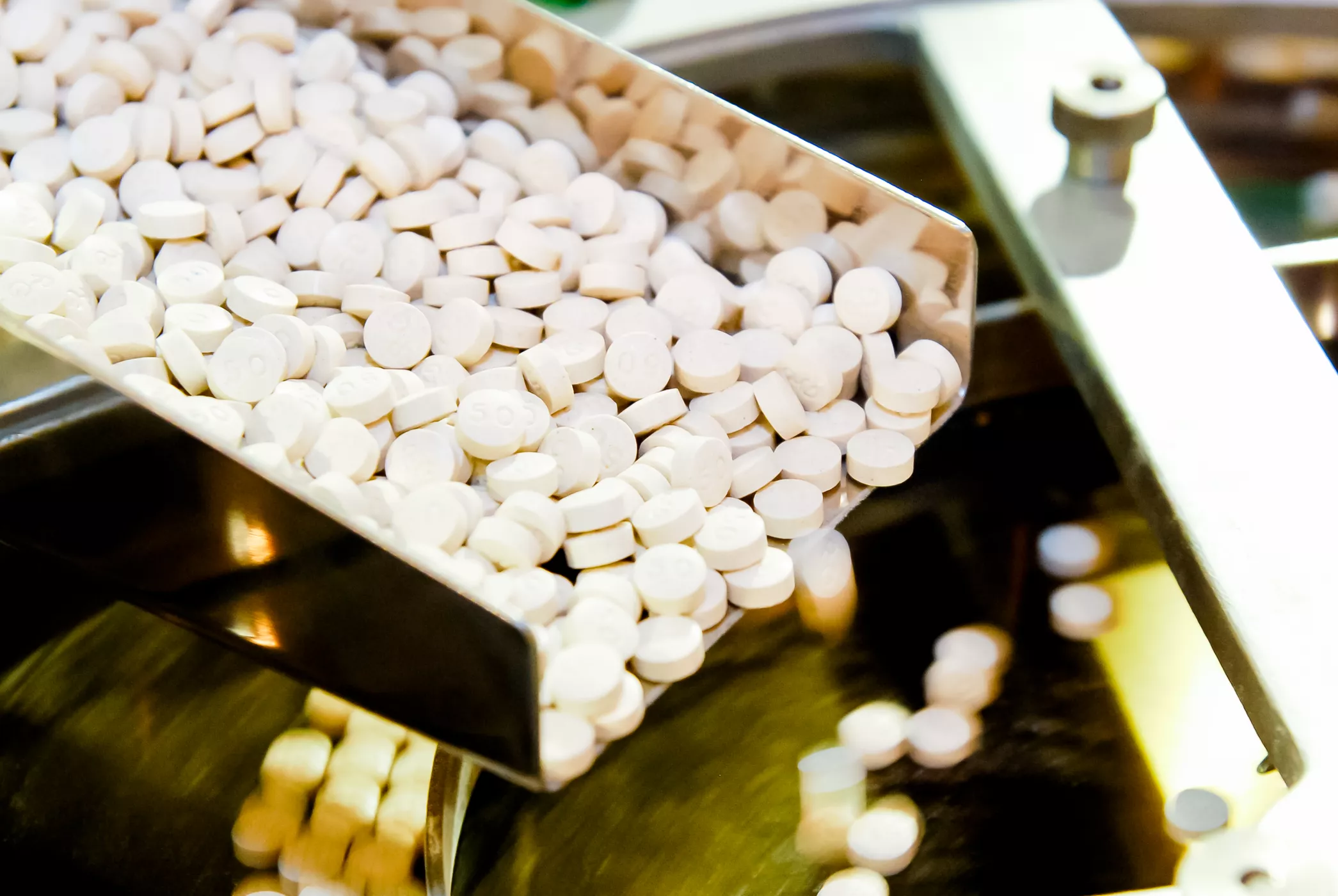 Closeup of pharmaceutical medicine tablet pill production in the rails