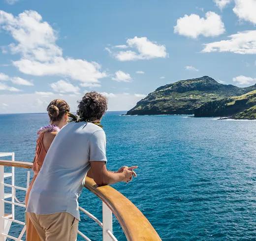 man and woman leaning on the rail of a cruise liner and enjoying the view