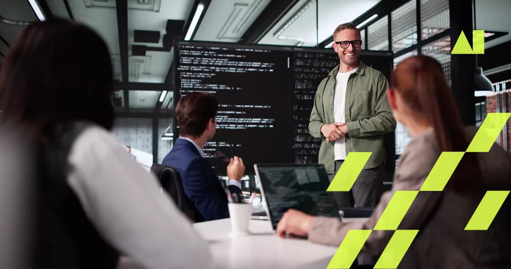 A group of professionals is gathered in a contemporary office space, focusing on a presenter standing in front of a large screen displaying lines of code. The setting suggests a collaborative work environment, possibly a software development or tech team meeting. The visuals include laptops, business attire, and geometric yellow overlays. No visible numeric values or identifiable brands are present.