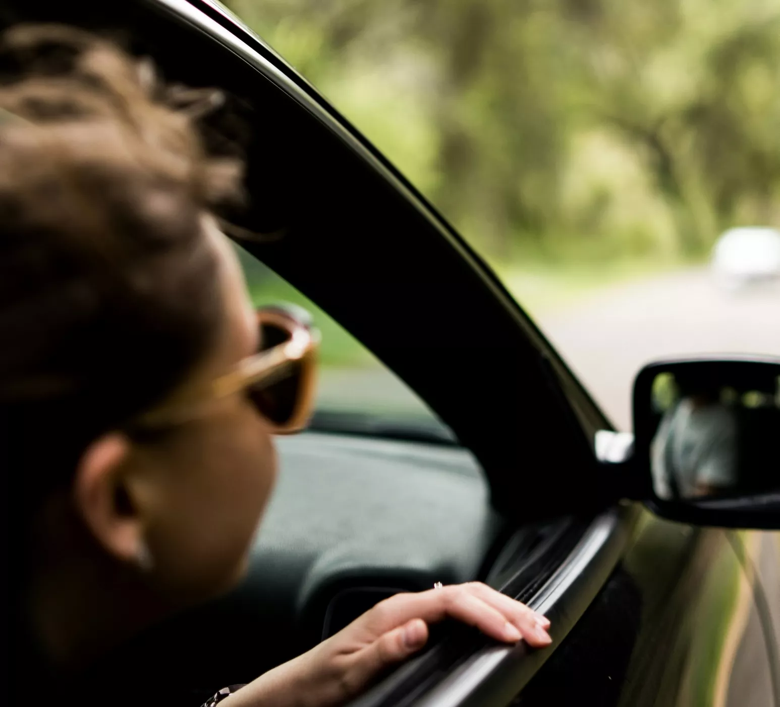 Passenger in black car with head looking out the open window
