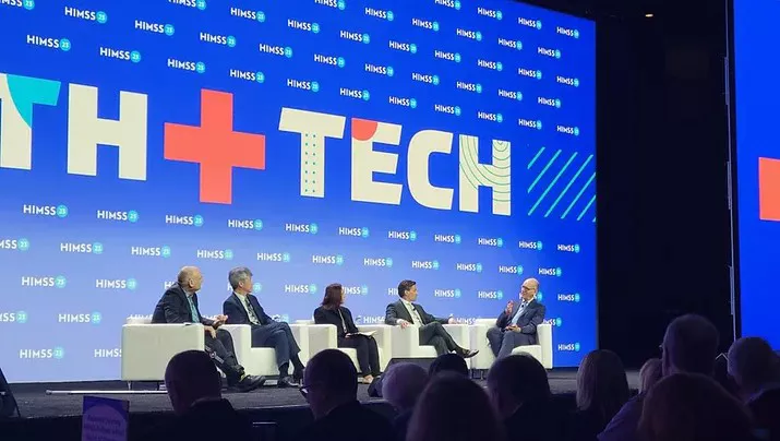 Leaders from Microsoft, Mayo Clinic, Virtue, and the World Economic Forum seated in white chairs on stage at HIMSS23.