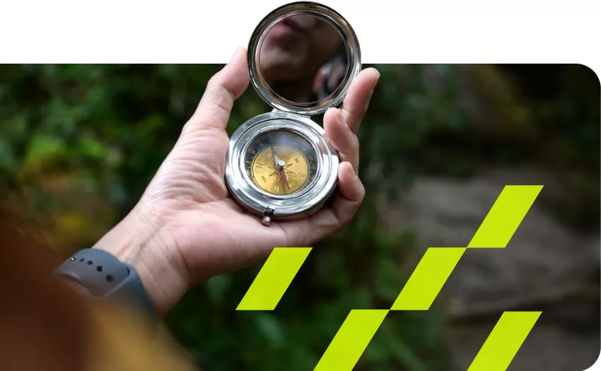 hand holding a compass in the middle of a jungle