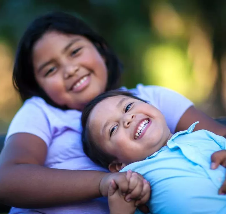 A brother and sister holding hands and smiling