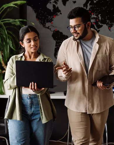 Two people working with a laptop in an office.