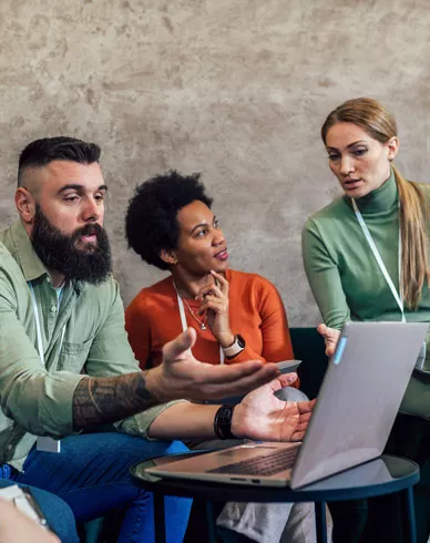 Group of people sitting on couch with laptop open on table