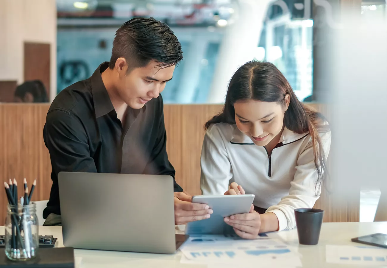 Two people work in the office with software. 