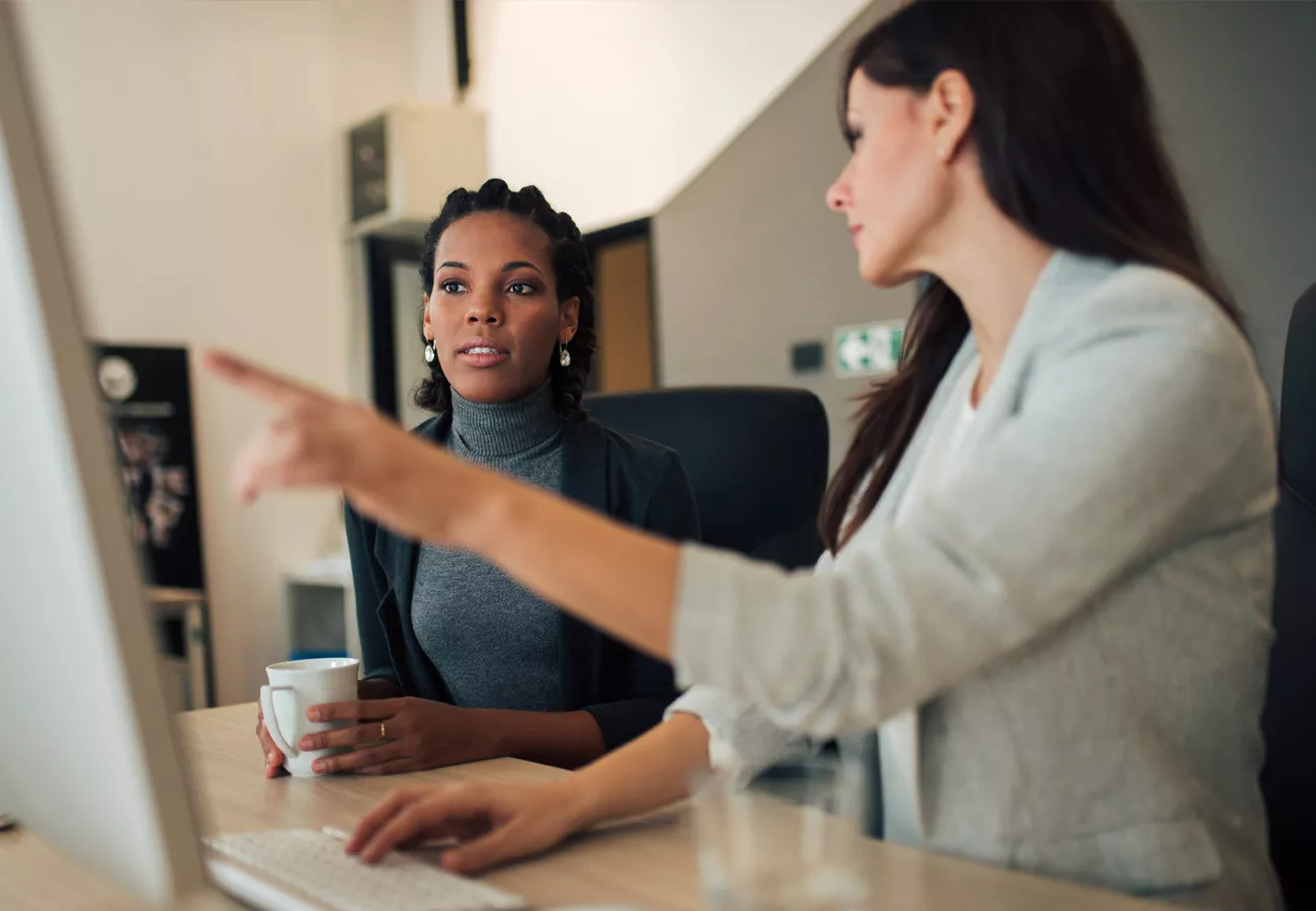 Two women work in the office at a computer.