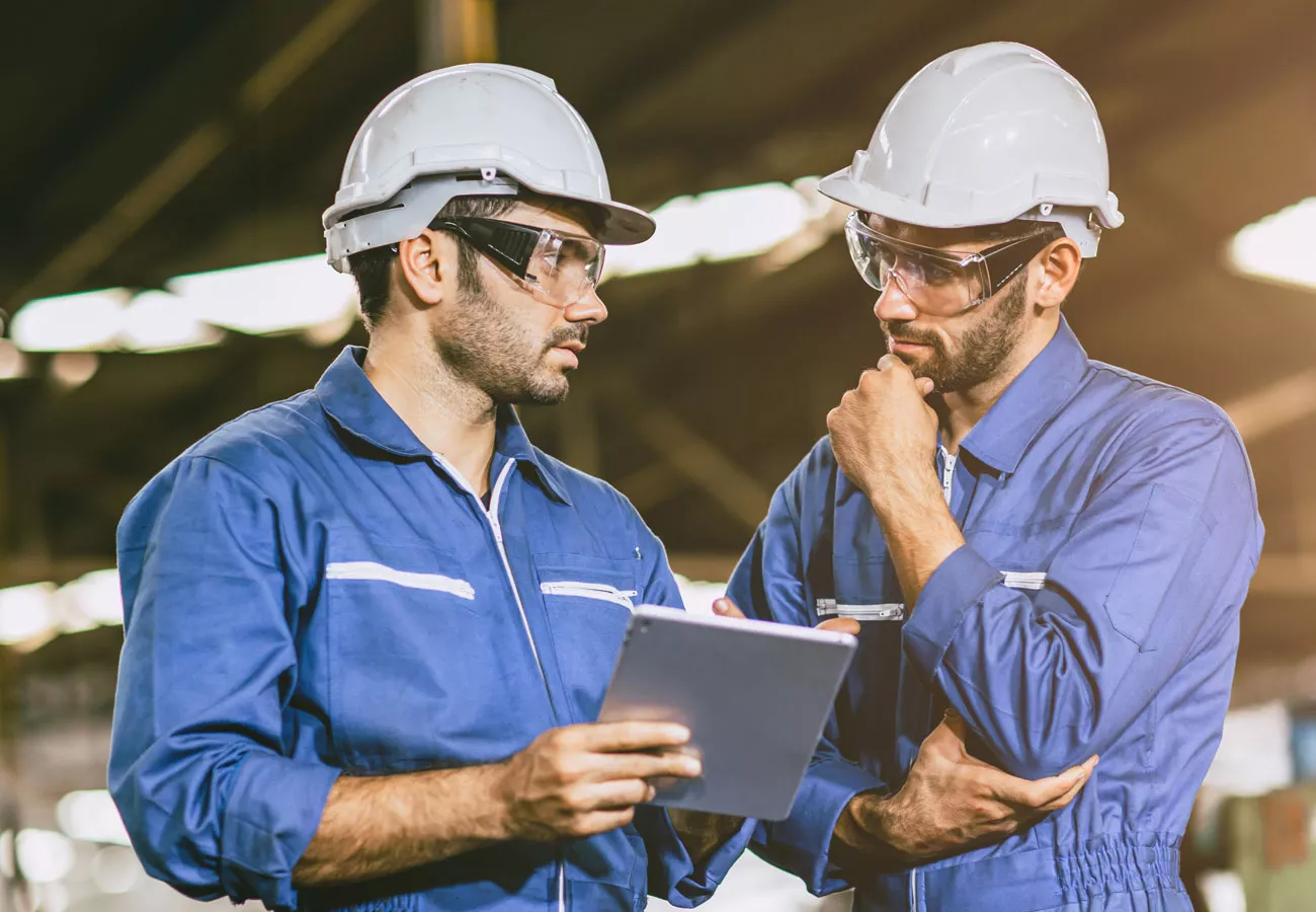 Two men work together to solve a problem in an industrial facility.