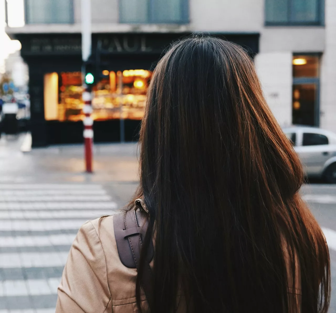 Woman with long brunette hair walk down street past retail stores