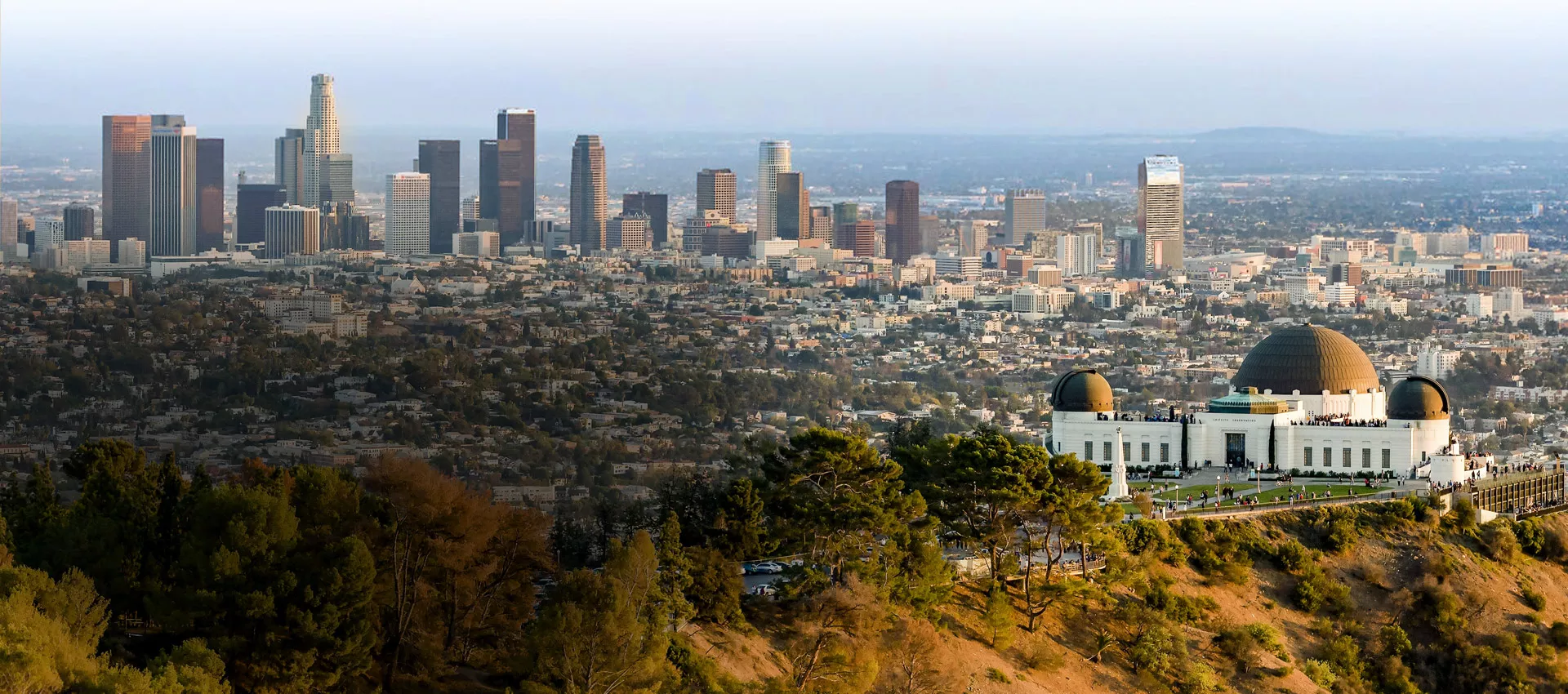 The Griffith Observatory sits in front of the Los Angeles skyline and city below the hill.