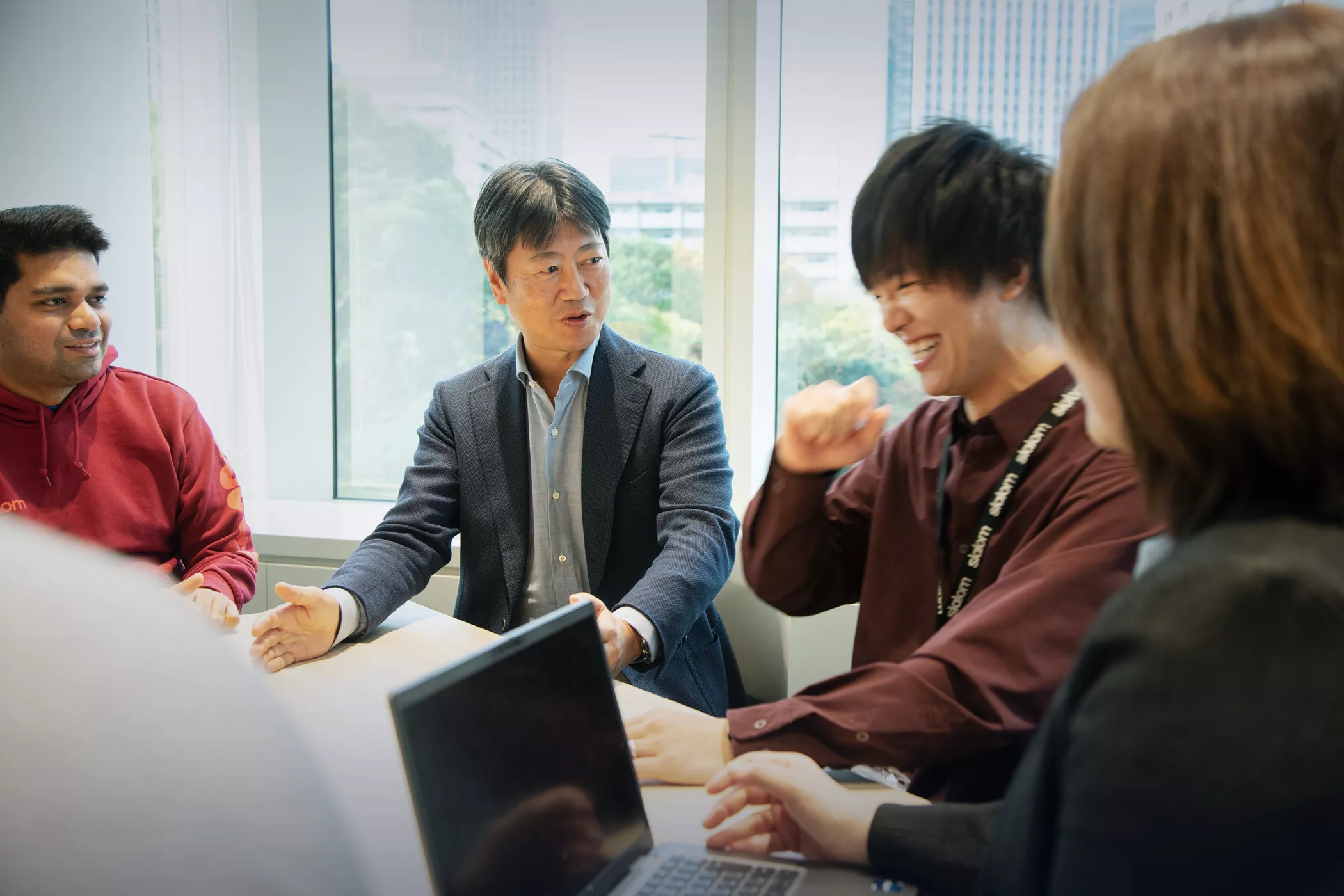 Satoshi Watanabe talking to coworkers in a meeting room