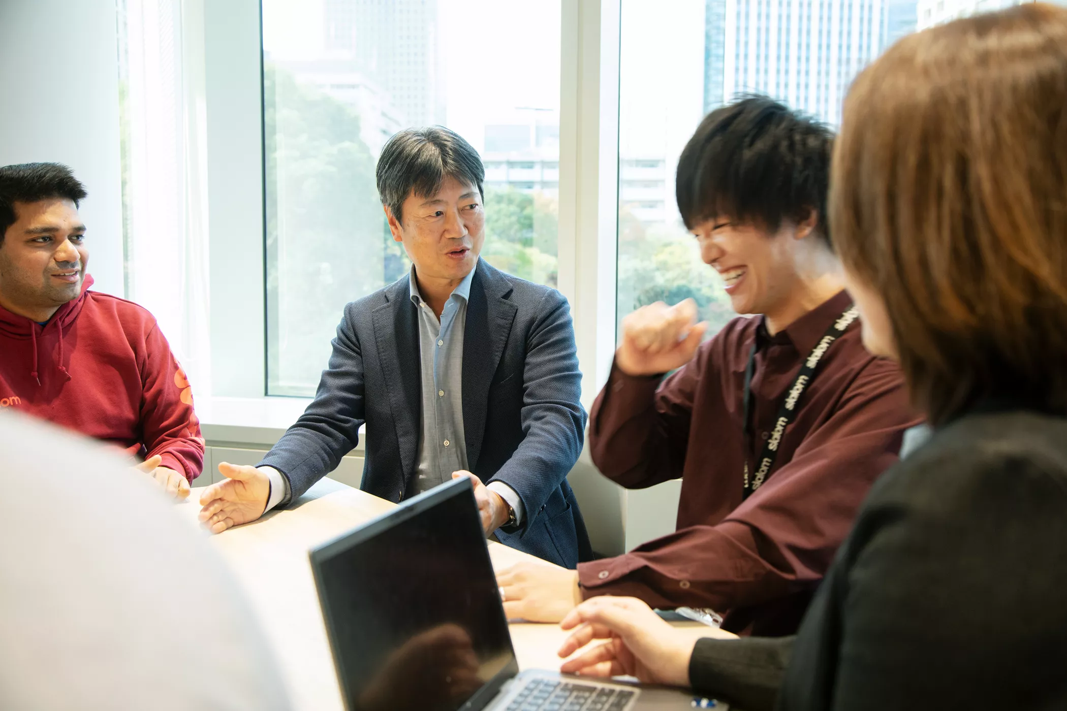 Satoshi Watanabe talking to coworkers in a meeting room