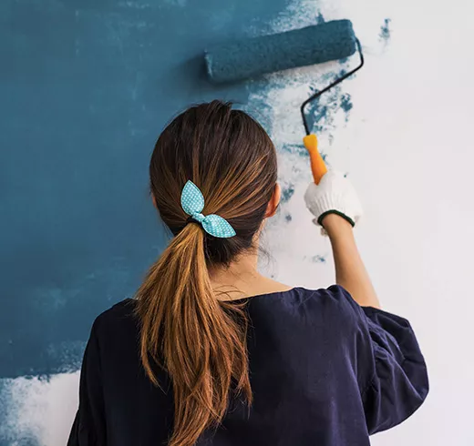 Woman painting a wall with a roller