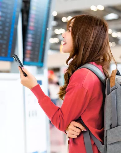 A woman looks at departure information screens in a large airport.