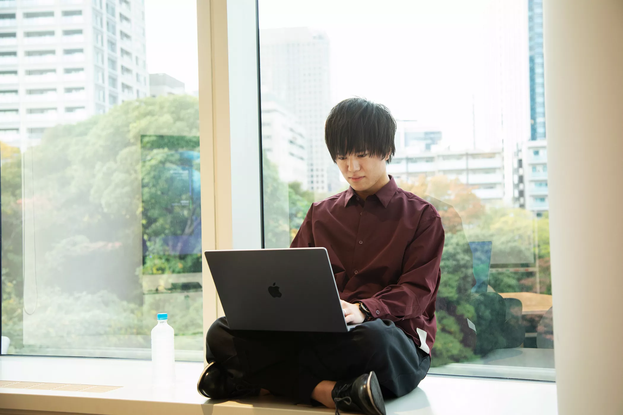 Takuma Doi sitting in front of a window