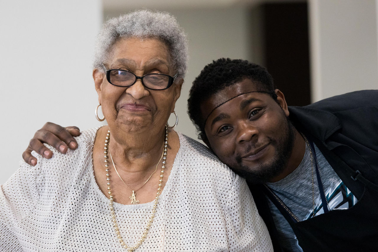 Older adult with younger person with arm around shoulder