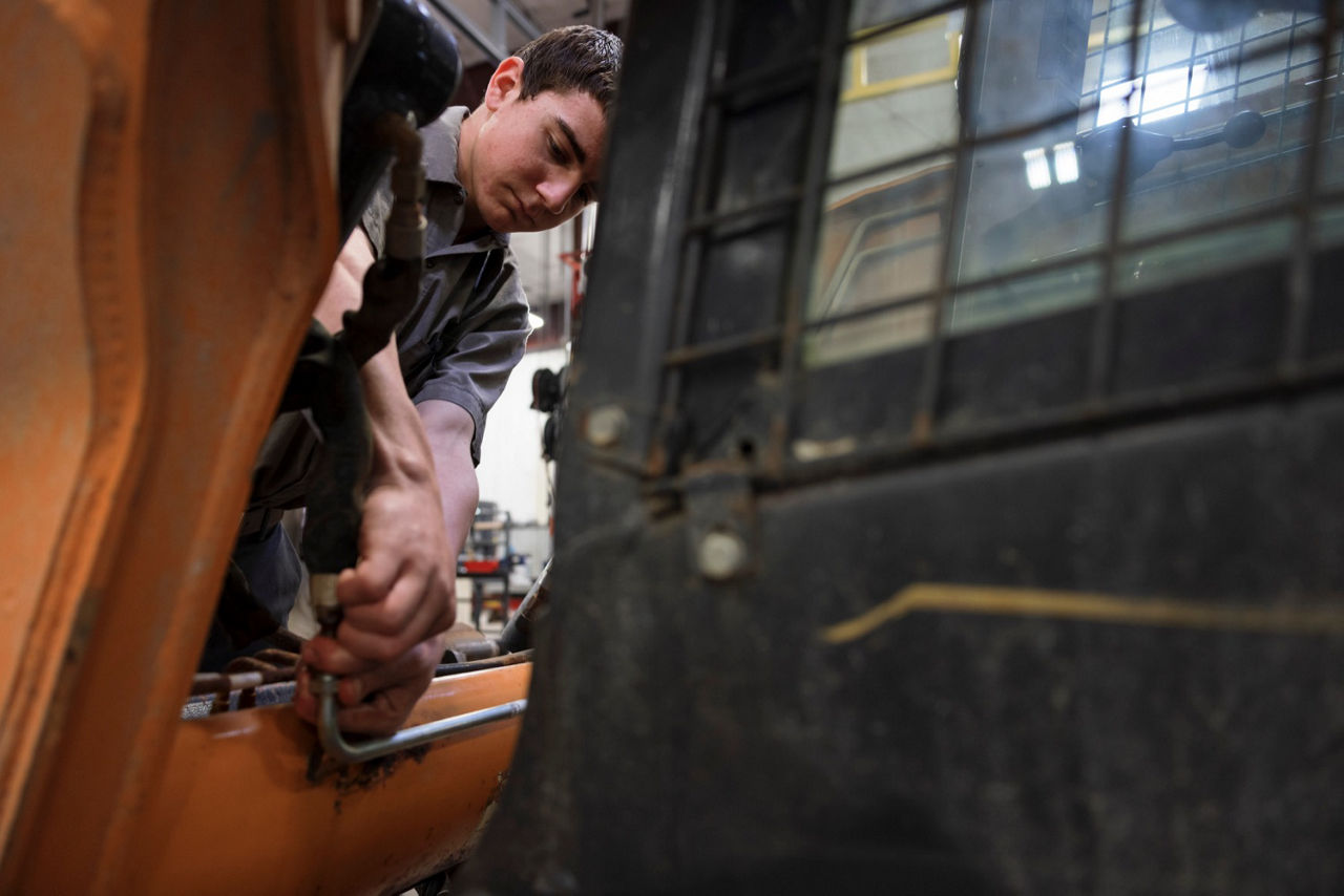 A pre-apprentice technician works on a machine.