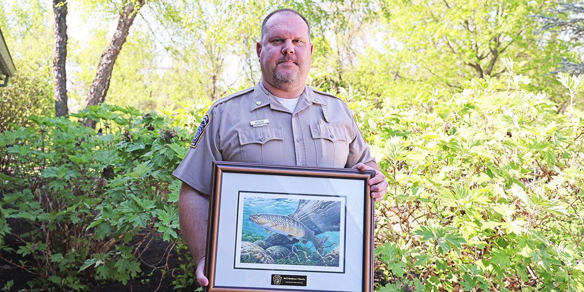 2023 NECLECA Officer of the Year Award Recipient, Matthew J. VIsosky holding a framed picture of a brown trout.