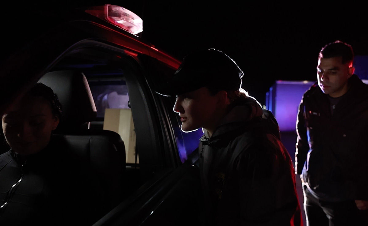 Two Hill Impact cadets with a driver in a vehicle during a mock traffic stop at night